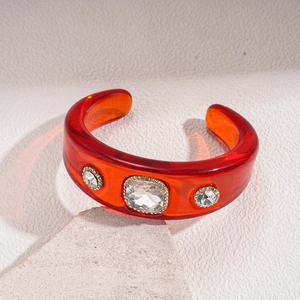 Detail view of a vintage red resin open bangle with luxury inlaid rhinestones
