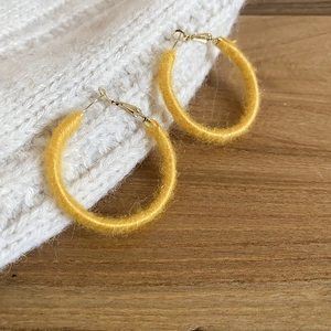 Detailed view of yellow mohair wrapped hoop earrings showing soft texture and metal hooks
