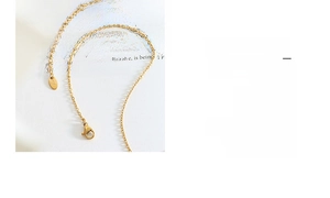Detailed close-up of 18K gold chain with lobster clasp and adjustable link tag