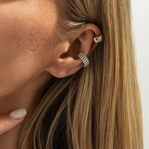 Macro detail of silver layered bead and wide smooth metal ear cuffs on model's ear