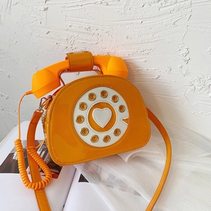 Detail of yellow patent leather handbag with vintage phone dial and heart detail