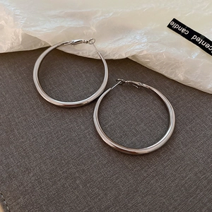 Detailed close-up of shiny silver hoop earrings on a textured grey and white background