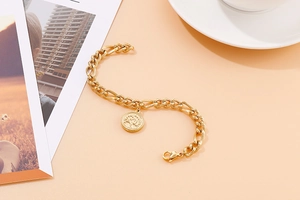 Detailed view of golden stainless steel bracelet with life tree coin charm on orange background
