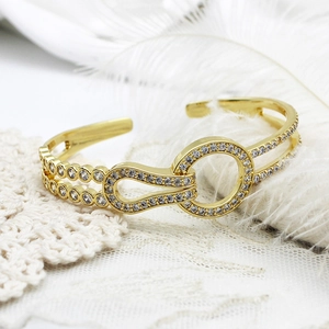 Detail of 18K gold-plated open bangle featuring CZ micro-pave geometric interlocking loops