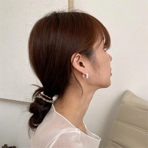 Close-up of minimalist silver hoop earrings with texture worn by a model in soft lighting