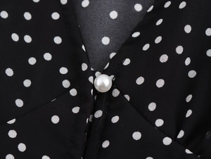 Detail of V-neckline on polka dot dress featuring a decorative pearl button closure