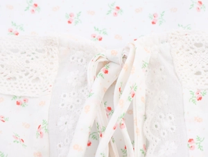 Detail aus floralem Stoff mit Spitzen-Patchwork und Kordelzug-Knoten-Dekoration