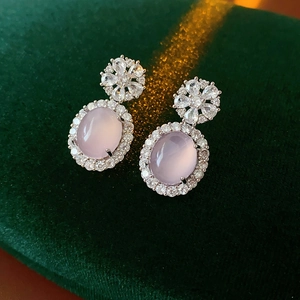 Gros plan de boucles d'oreilles vintage en calcédoine rose et zircons sur velours