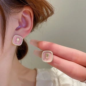 Close-up of pink enamel square earring with gold tulip relief and pearl border