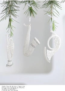 Glittery white musical instrument ornaments hanging on a green Christmas tree branch