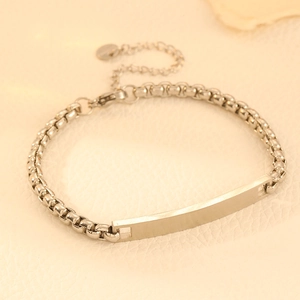 Detail shot of a silver stainless steel box chain bracelet featuring an engravable bar plate