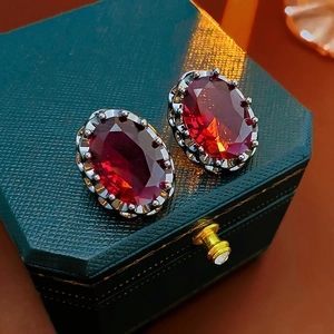 Macro shot of vintage style earrings with red oval zircon set in dark metal
