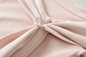 Detailed view of pink knitted fabric featuring unique twist knot and ribbed texture detail