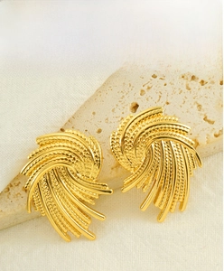 Close-up of golden woven spiral earrings with intricate metal texture and stylish design