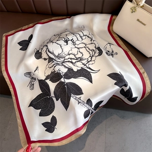 Detail of floral and bird line art on a white silk scarf with red and beige borders