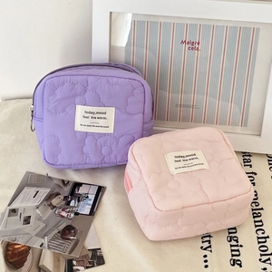 Detailed view of quilted flower coin purses in lavender and pink with cloud texture