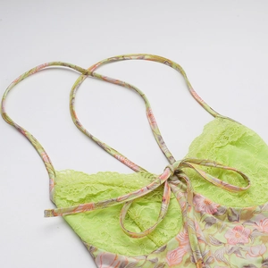 Détail d'une robe fleurie avec dentelle vert citron et fines bretelles croisées réglables