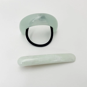 Detail of light green resin hair clip and U-shaped elastic band set on white background