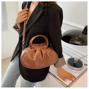 Brown pleated cloud bag shown with model in elegant black blazer and office setting