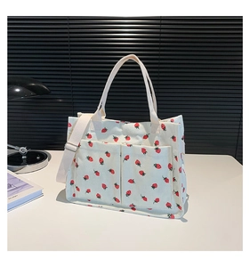 Detail of white corduroy tote bag with strawberry print and two front pockets