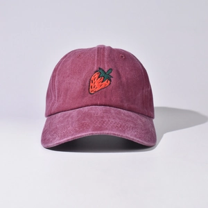 Dettaglio del ricamo a fragola su un cappellino da baseball in cotone lavato