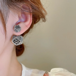Macro side view of vintage silver double-sided earrings with textured granular surface