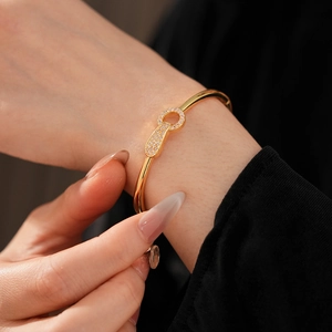Close-up of gold plated bangle featuring a pave-set zircon clasp on model wrist