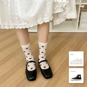 Ballet style cream crew socks with black bows and lace edges on wooden floor