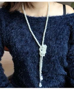 Detail of long French baroque pearl necklace styled on a blue sweater with a unique knot