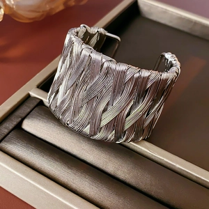 Close-up of vintage braided open cuff bracelet in silver on a dark leather jewelry tray
