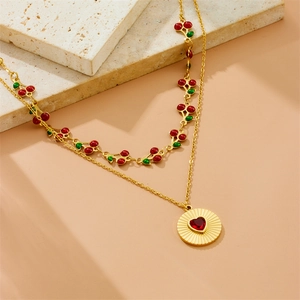 Gold double-layered necklace with red cherry pendants and a heart sunburst medallion