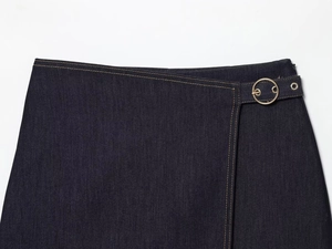 Détail d'un pantalon en jean bleu foncé avec boucle dorée et coutures contrastées