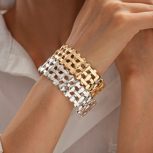 Close-up of gold and silver woven layered bracelets on model wearing a white shirt