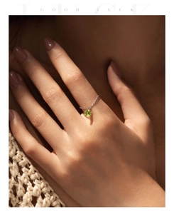 Detail of s925 silver chain ring featuring a round green gemstone on woman finger