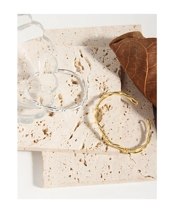 Detailed view of woven knot open bangles in gold and silver finish on stone