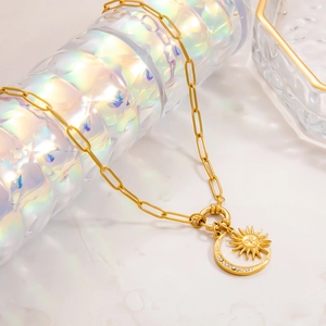 Detail of 18k gold paperclip chain with crystal moon and sun pendants on display