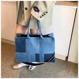 Detail of multi-tone denim patchwork tote bag with shoulder strap worn by a model