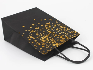 Detail of premium black paper gift bag featuring shiny gold foil heart patterns and rope handles
