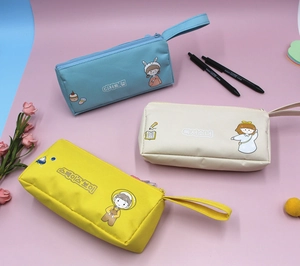 Dettaglio di tre astucci in tela nei colori blu, beige e giallo con graziose stampe cartoon