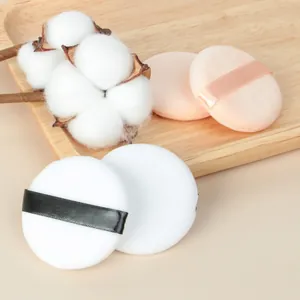 Soft crystal velvet powder puffs in pink and white on a natural wooden tray with cotton