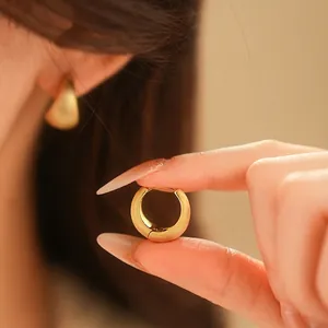 Minimalist geometric brushed gold chunky hoop earrings worn for a luxury fashion look