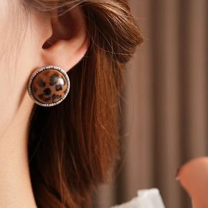 Gros plan macro d'une boucle d'oreille vintage léopard ronde avec bord argenté sur l'oreille