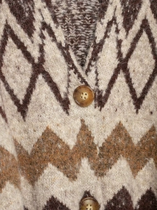 Macro shot of knitted cardigan showing geometric patterns and amber textured buttons