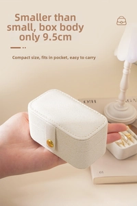 Close-up of 9.5cm mini travel jewelry box in cream PU leather held by hand