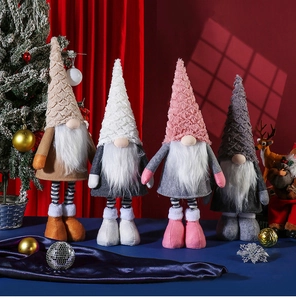 Detail of four Christmas gnomes in pink and grey with knitted hats on blue velvet