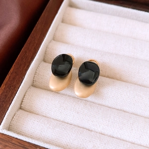 Macro detail of minimalist two-tone oval stud earrings in a velvet jewelry organizer box
