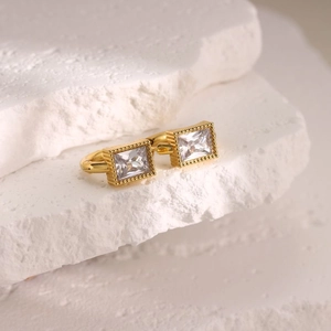 Macro shot of 18K gold plated rectangular earring with zircon on white stone
