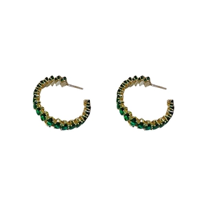 Gold C-shape hoop earrings with emerald green zircon stones on a white background