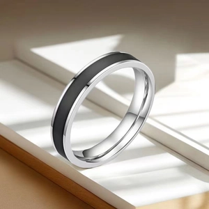Detail view of silver stainless steel ring with black enamel inlay on neutral background