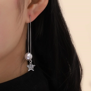 Close-up of star and pearl drop earring chain worn for an elegant feminine style